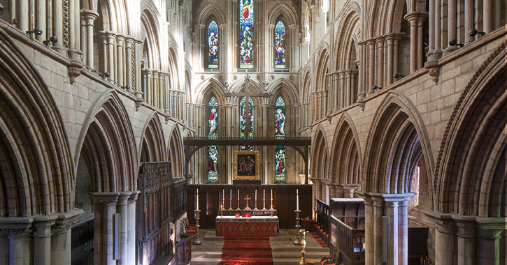 Interior view of Hexham Abbey with stained glass windows in background.